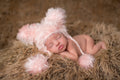 Newborn baby peacefully sleeping on soft textured blanket wearing The Daisy Baby LLC - Pink Bear Crocheted Handmade Heirloom Cute Baby Gift Hat, a cozy and stylish accessory perfect for baby boutique collections and newborn gifts.