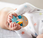 Baby holding a Rattlefish Wooden Baby Rattle with soothing blue and natural wood tones, designed for sensory play and safe for newborns.