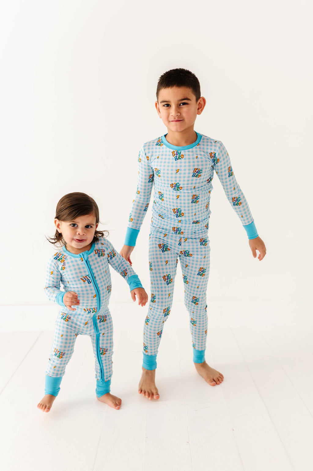 Two children wearing matching blue pajamas with cartoon characters on a white background