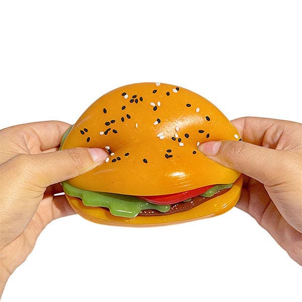 Hamburger-shaped stress reliever toy held by two hands on a white background