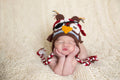 Newborn baby wearing The Daisy Baby LLC - Brown/White Pirate Owl Crocheted Handmade Heirloom Gift Hat, posed on a soft cream knit blanket in a cozy, stylish children’s boutique setting.