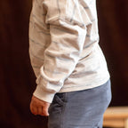 Person wearing a striped long-sleeve shirt and blue jeans against a dark background