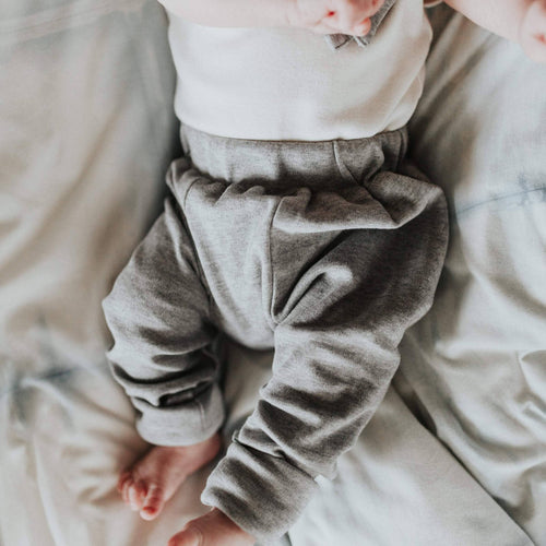 Close-up of a baby wearing Finn + Emma - Baby cuffed pants | heather organic in soft neutral tones, showcasing breathable, cozy fabric perfect for stylish kids clothing and modern baby style.