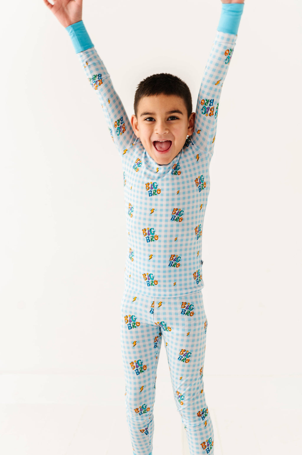 Child wearing a blue checkered onesie with cartoon characters on a white background