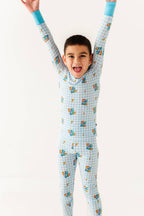 Child wearing a blue checkered onesie with cartoon characters on a white background