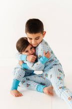 Two children in matching pajamas hugging on a white background