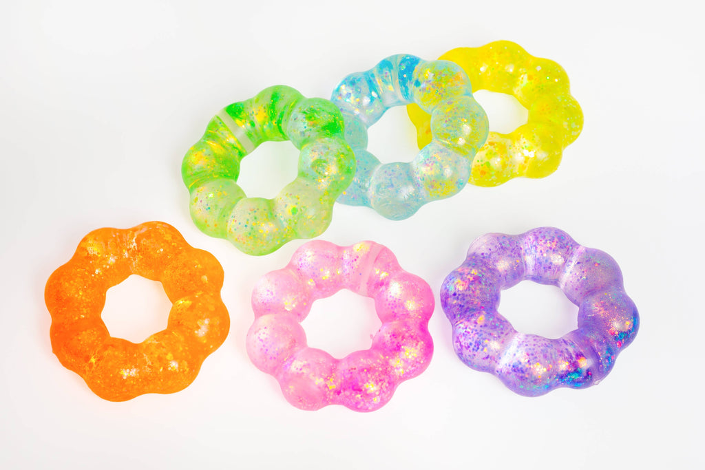 Five flower-shaped translucent slime rings in assorted colors, including orange, pink, purple, green, blue, and yellow, arranged on a plain white background.