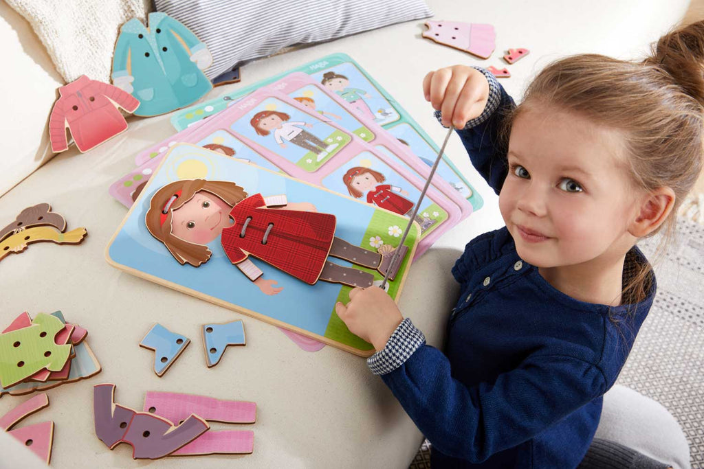 Young child playing with the Dress Me Threading & Lacing Game, an educational toy encouraging imaginative play and fine motor skills development in a cozy setting.