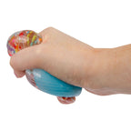 Hand squeezing a blue stress cupcake against a white background