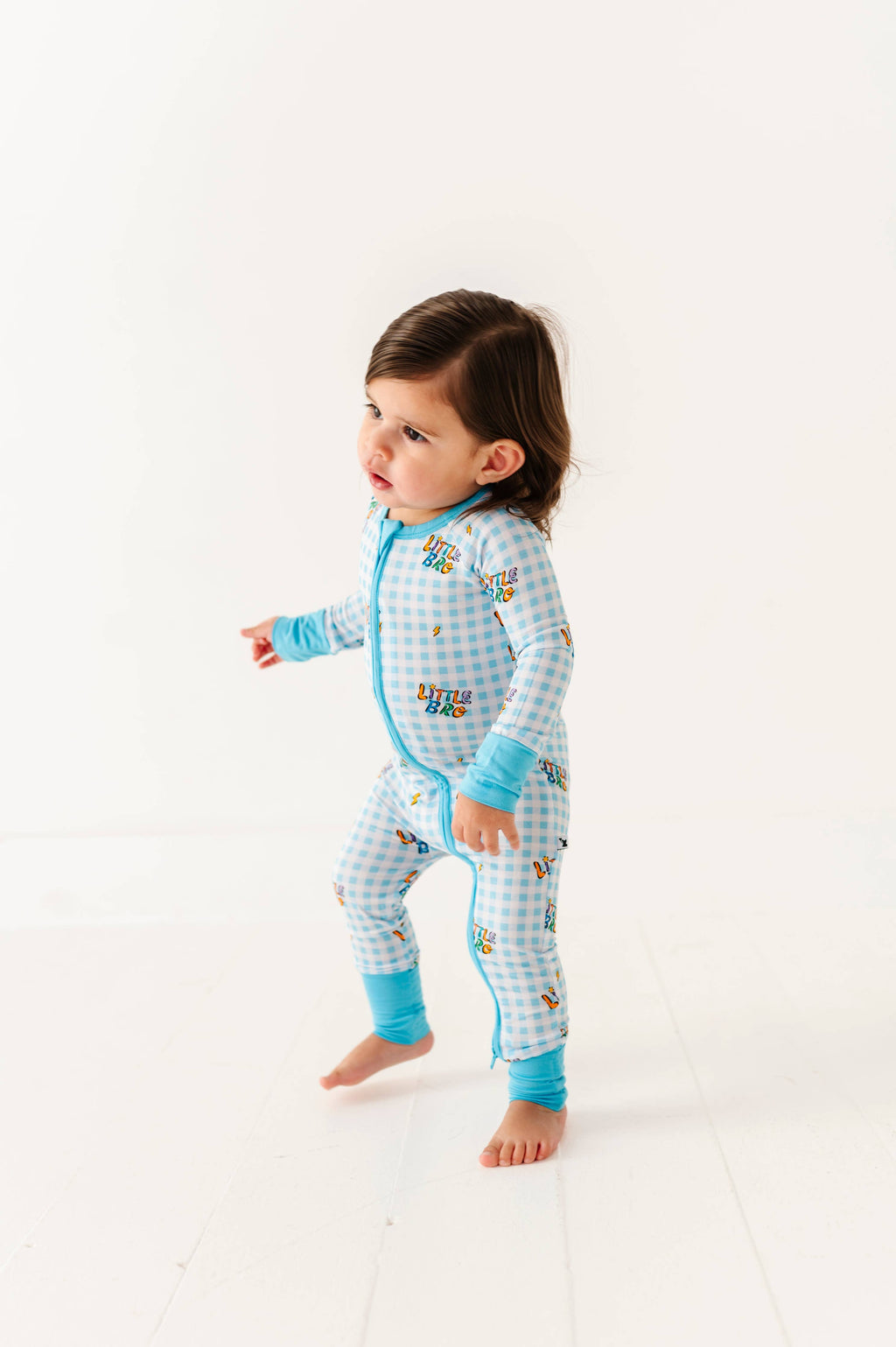 Child wearing a blue checkered onesie with cartoon characters on a white background