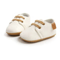 Pair of Urban Tots - Taylor Leather Kicks - Ivory baby shoes featuring soft ivory leather, tan laces, and flexible soles, perfect for stylish kids in a curated children’s boutique.