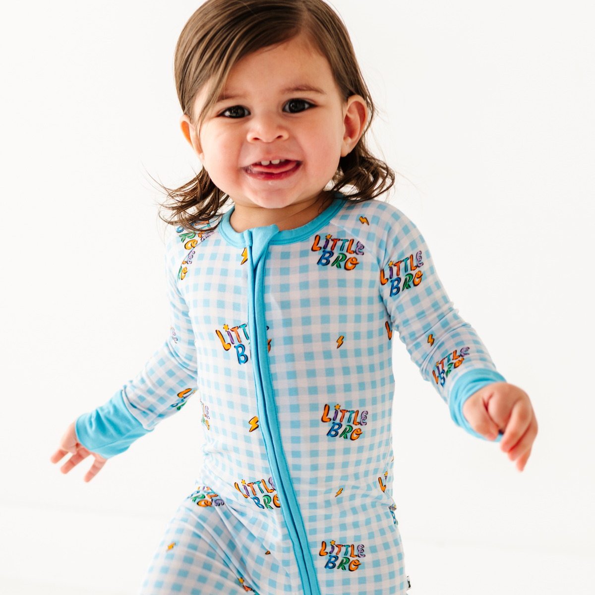 Child wearing a blue 'Little Bro' onesie on a white background