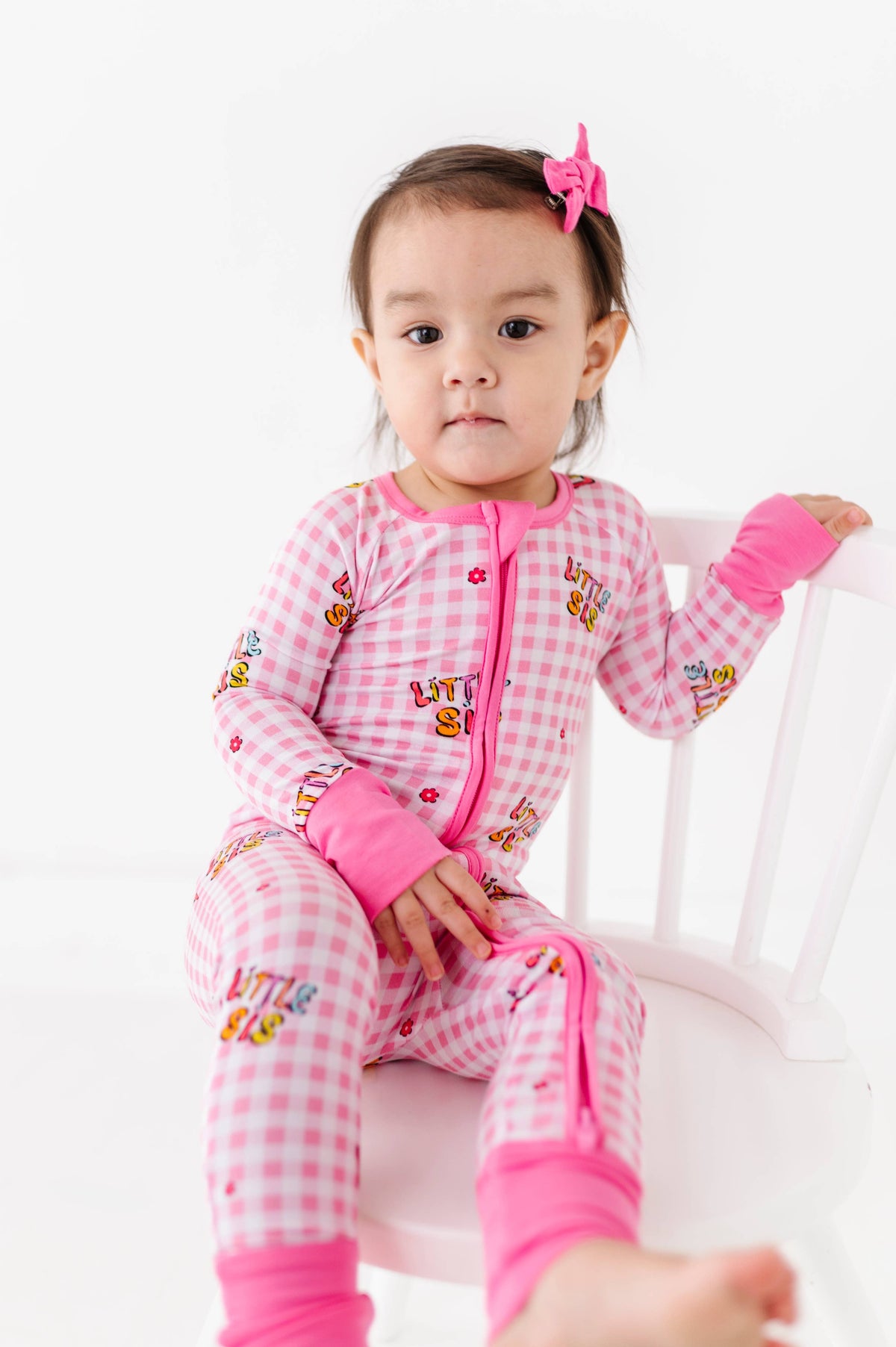 Child wearing pink checkered pajamas with cartoon characters on a white background