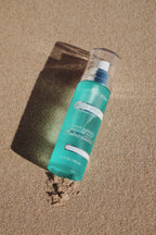 True Ocean - True Ocean: Body Spray - 3.4oz. bottle with a fresh turquoise design lying on sandy beach, evoking a light, sun-kissed coastal scent.