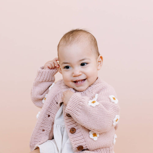 Smiling baby wearing The Blueberry Hill - Flower Cardigan Blush Baby Sweater Kids Spring Summer, cozy and stylish knitwear perfect for a curated children’s boutique collection.