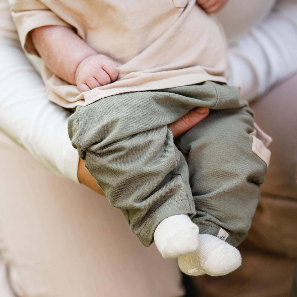 Close-up of infant boy wearing Burt's Bees Baby - Drop Shoulder Infant Boy Tee Set, featuring soft neutral tones and cozy breathable fabrics for stylish kids clothing in a curated children’s boutique.