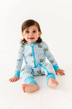 Baby wearing a blue checkered outfit with cartoon characters on a white background