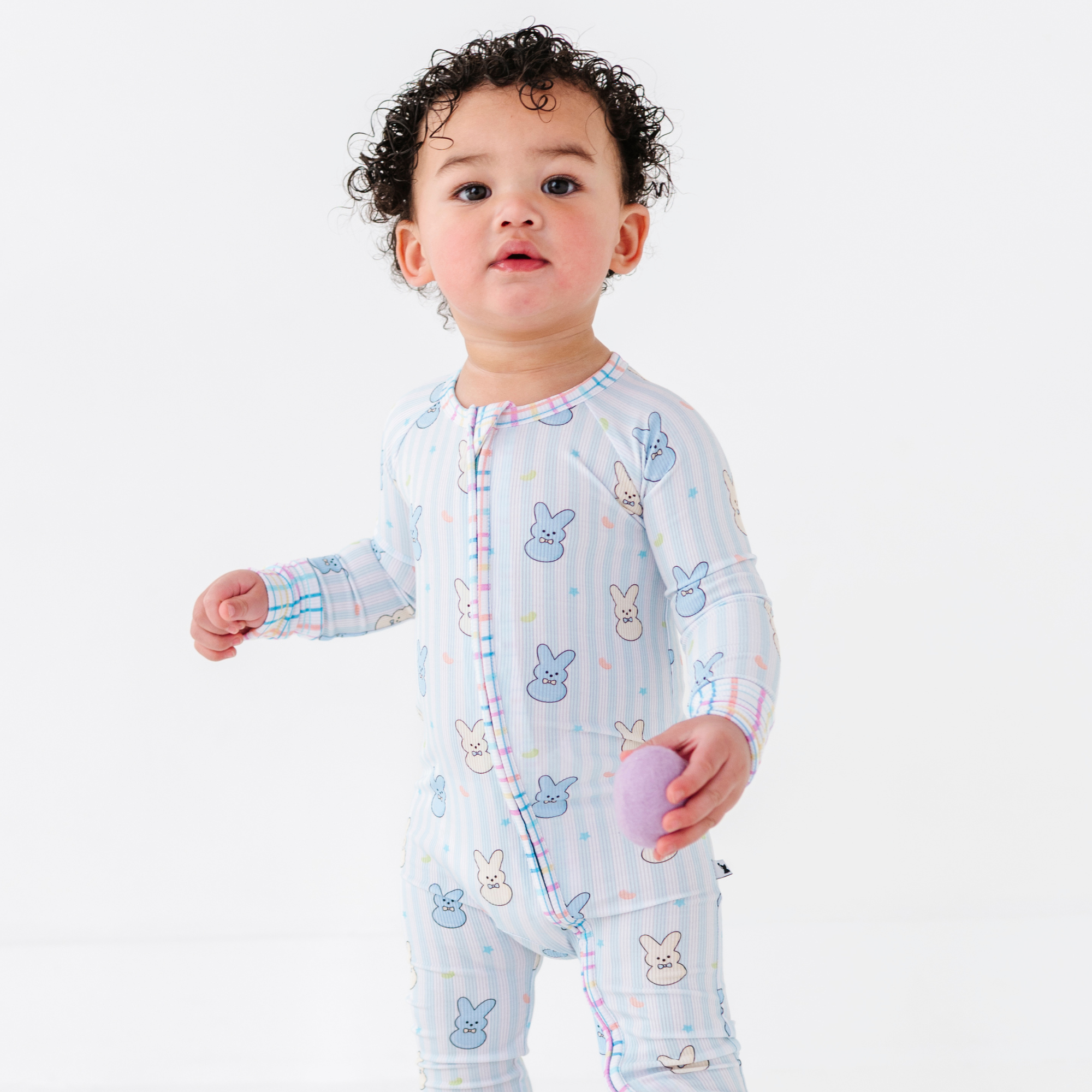 Baby wearing Kiki + Lulu - Peeps + Sleeps Convertible Footies featuring pastel bunny prints on soft fabric, ideal for cozy baby essentials from a curated children’s boutique.