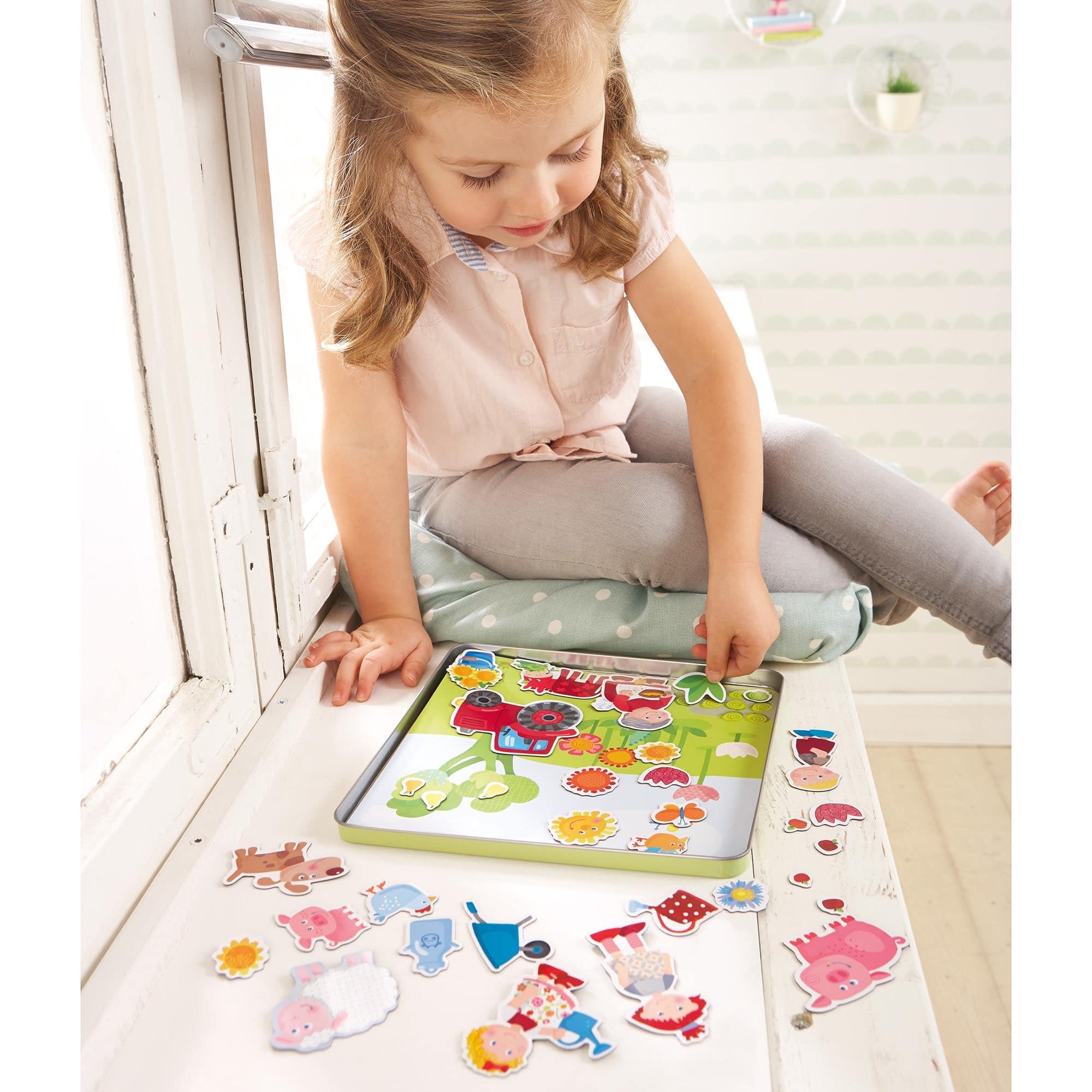 A young child playing with Peter and Pauline's Farm Magnetic Game, arranging colorful farm animal and character magnets on a board, encouraging imaginative play and learning.