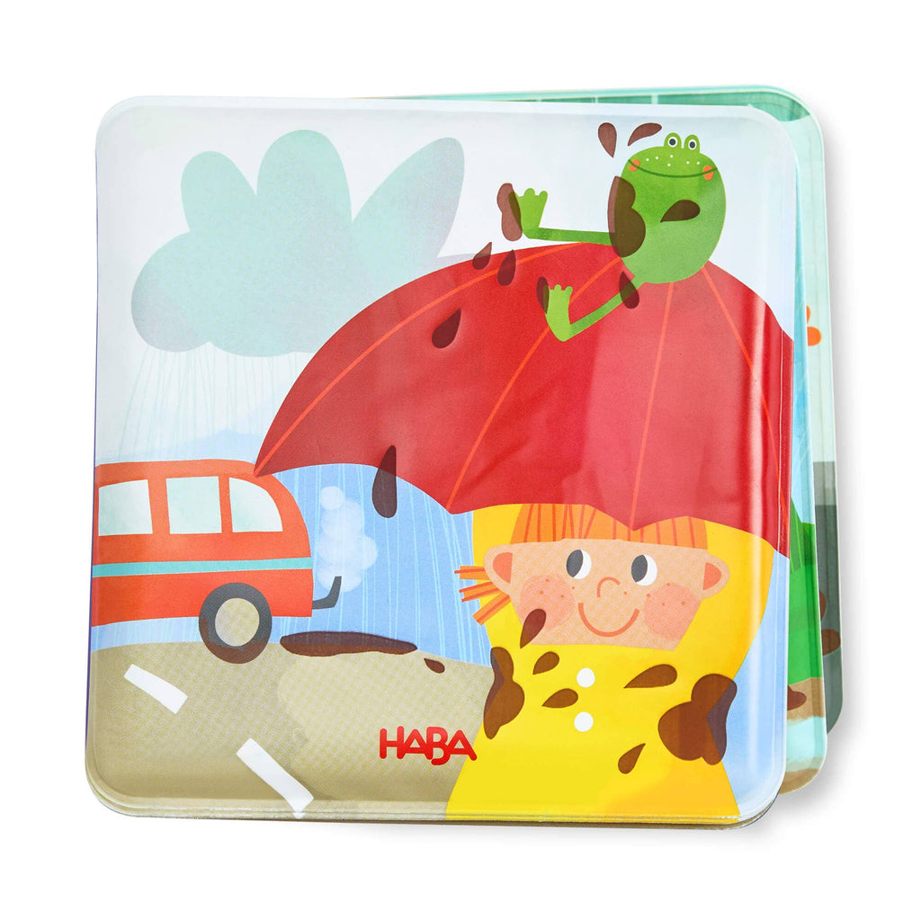 Magic Muddy Day Color Changing Bath Book featuring a cheerful child in yellow raincoat holding a red umbrella with a green frog and playful mud splashes, promoting imaginative play and sensory learning.