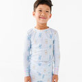 Young child wearing light blue pajamas with playful bunny print and pastel plaid details, featuring Kiki + Lulu - Peeps + Sleeps Kids Pajamas from a curated children’s boutique.