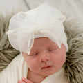 Newborn baby peacefully sleeping while wearing ilybean - White Chiffon Pearl Bow Newborn Girl Hospital: White, a delicate white hat with a pearl-accented chiffon bow, styled for cozy baby essentials from a curated children’s boutique.