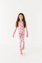 Young girl wearing a pink checkered onesie with cartoon characters on a white background