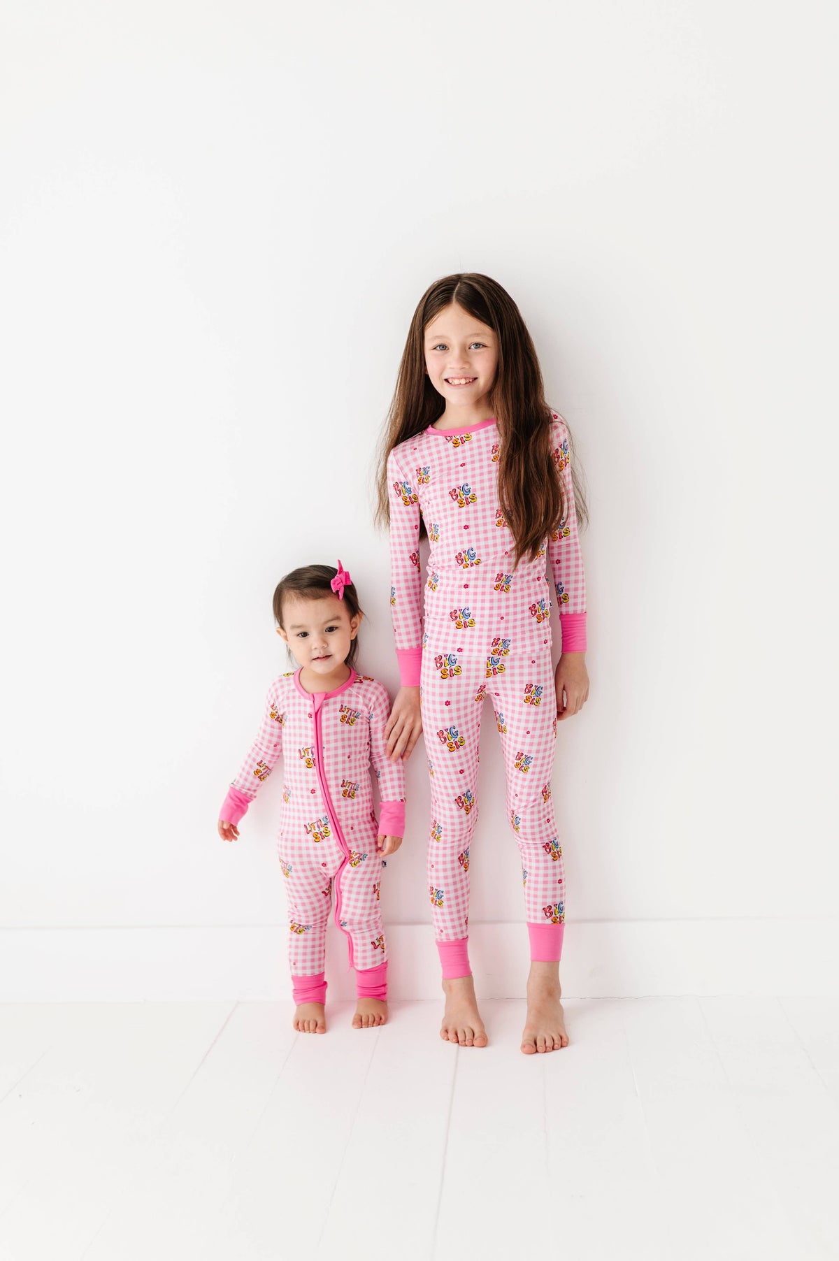 Two children wearing pink matching pajamas on a white background