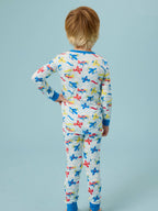 Child wearing RuffleButts + RuggedButts - SoftSnooze™ Kids Bamboo Viscose Plane Parade Long Sleeve Pajama Set featuring colorful airplanes on a soft neutral background, cozy and breathable for bedtime comfort.