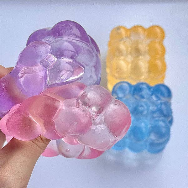 Colorful gummy bear-shaped soaps held by a hand against a light background