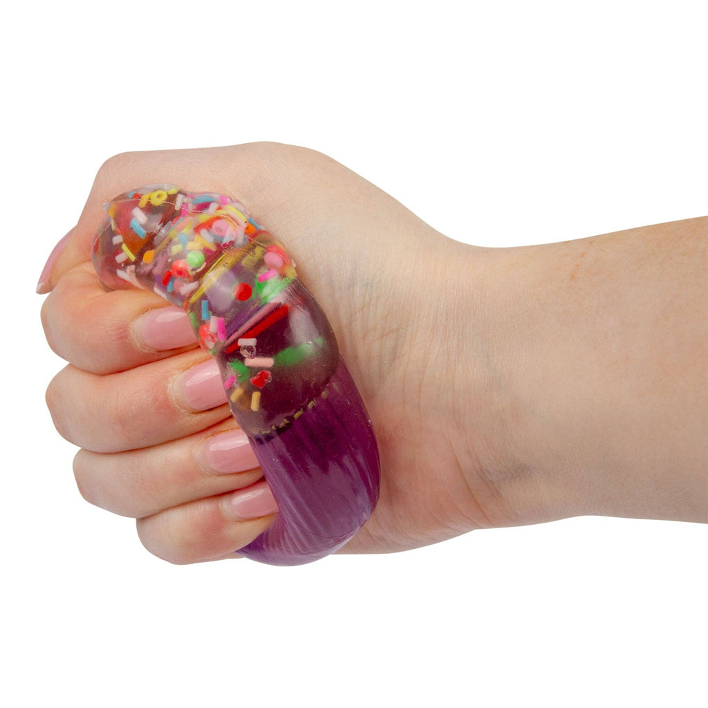 Hand holding a purple stress cupcake with colorful sprinkles on a white background