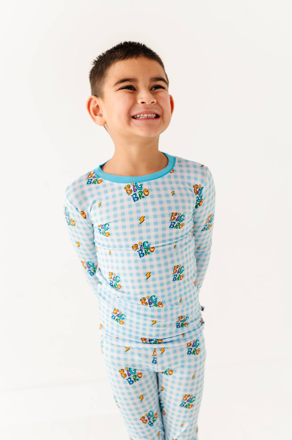 Child wearing a blue checkered pajama set with cartoon characters on a white background