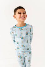 Child wearing a blue checkered pajama set with cartoon characters on a white background
