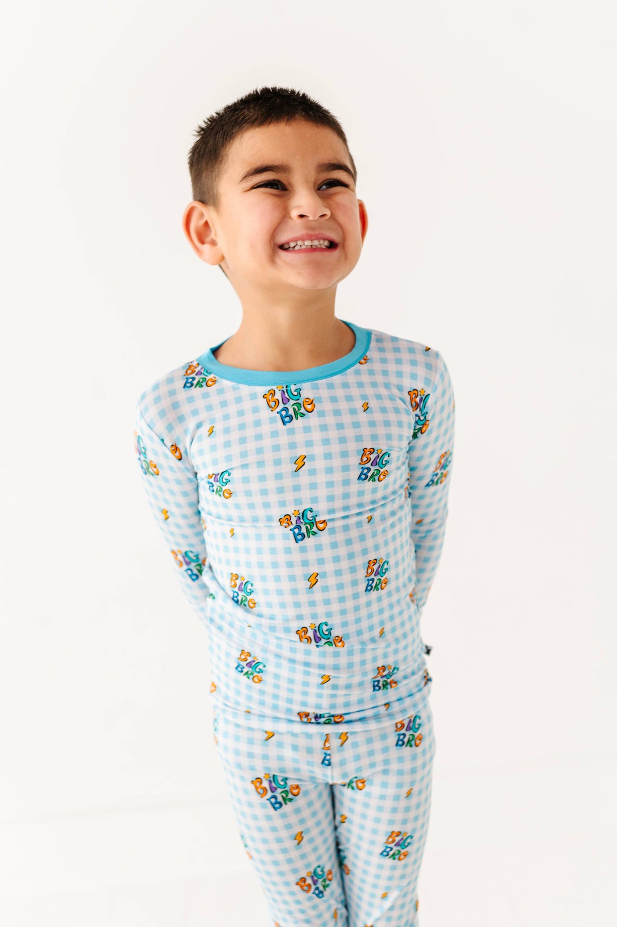 Child wearing a blue checkered pajama set with cartoon characters on a white background