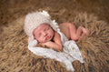 Newborn peacefully sleeping on a soft furry surface, wearing The Daisy Baby LLC - Beige/Cream Lace Crocheted Handmade Heirloom Baby Gift Hat, perfect for cozy baby essentials and stylish kids clothing.
