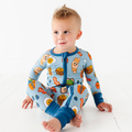 Toddler wearing the Kiki + Lulu - Blue Breakfast Convertible Footie featuring playful breakfast-themed illustrations on soft blue fabric, perfect for cozy baby essentials.