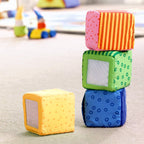 Soft colorful fabric blocks stacked on a floor play area showcasing the Happy Quartett Baby's 4 Piece Soft Block Set, ideal for sensory play and early learning.