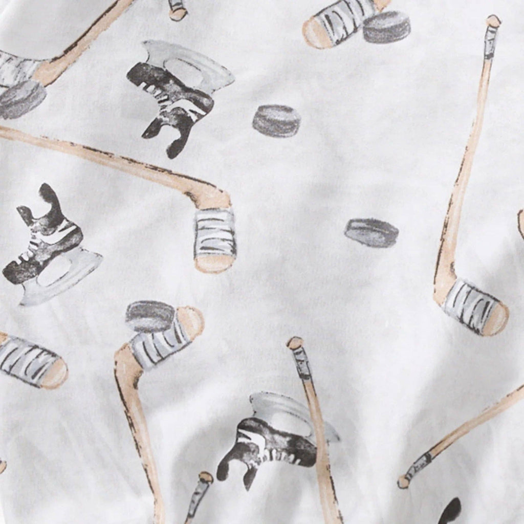 Close-up of soft fabric with a playful pattern of hockey sticks, skates, and pucks in neutral tones from the Burt's Bees Baby - Hockey Season Sweatshirt & Pants Set, designed for cozy baby clothing at a curated children’s boutique.