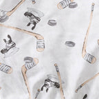 Close-up of soft fabric with a playful pattern of hockey sticks, skates, and pucks in neutral tones from the Burt's Bees Baby - Hockey Season Sweatshirt & Pants Set, designed for cozy baby clothing at a curated children’s boutique.