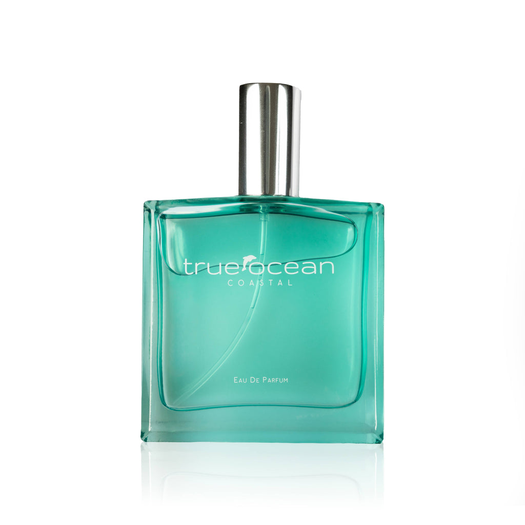 Clear turquoise glass perfume bottle with silver cap labeled True Ocean - Coastal - a beach perfume, showcasing a fresh and ocean-inspired scent for modern moms.