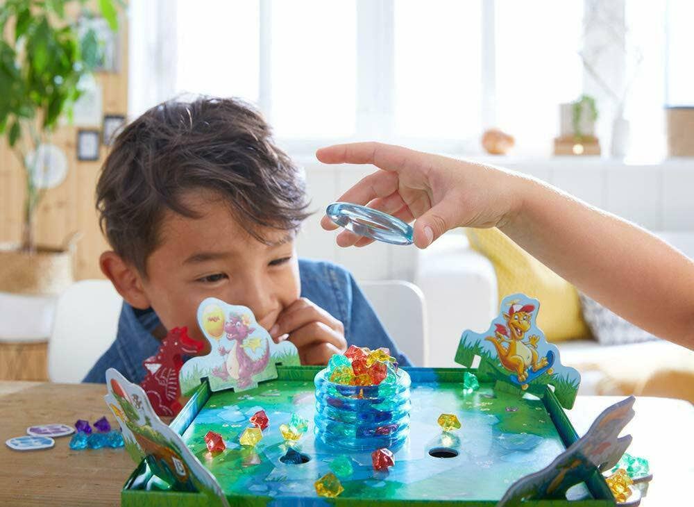 Children playing Dragon's Breath Game with colorful dragon figures and gems, promoting imaginative play and educational fun in a bright, cozy setting.
