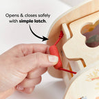 Hand holding a simple red wooden latch on the Underwater World Wooden Shape Sorter, demonstrating how it opens and closes safely for child-safe play and educational fun.