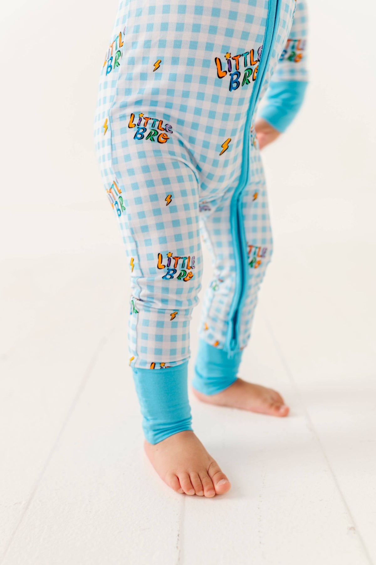 Children's blue checkered onesie with 'LITTLE BRO' text on a white background