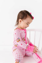 Child wearing a pink checkered outfit with cartoon characters on a white background