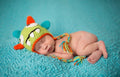 Newborn baby sleeping peacefully on a blue crocheted blanket wearing The Daisy Baby LLC - Lime Monster Tassels Crocheted Handmade Heirloom Gift Hat with vibrant colors and playful design.