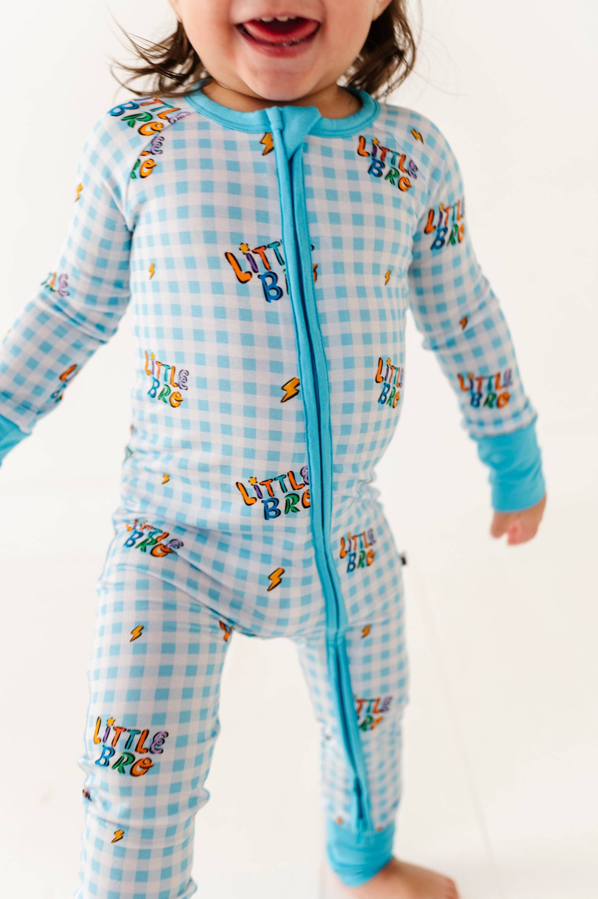Child wearing a blue checkered outfit with 'LITTLE BRO' text on a white background