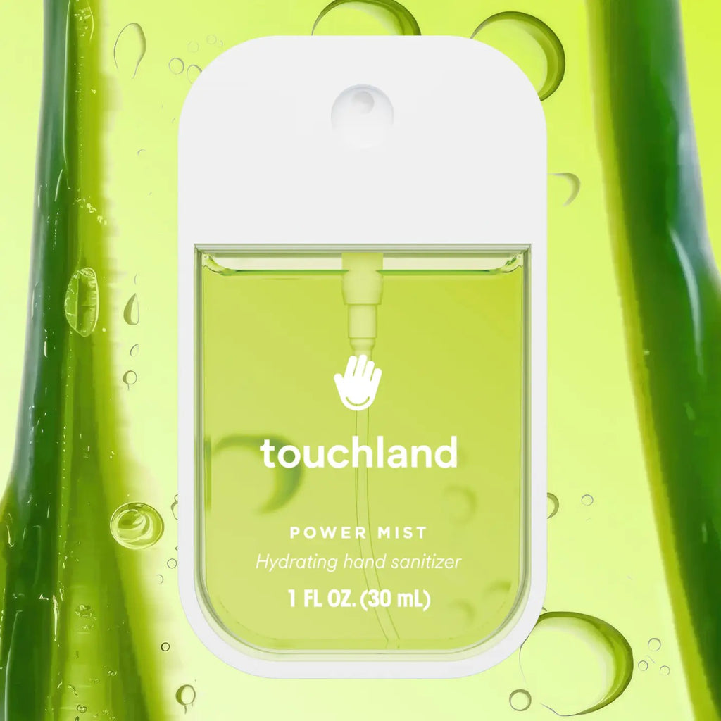 A 1 fl oz (30 mL) Touchland Power Mist hydrating hand sanitizer dispenser bottle, featuring a white cap and a translucent green body, set against a matching green liquid background with water droplets.