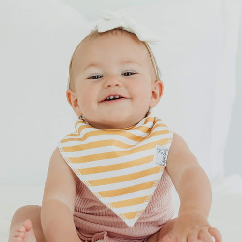 Baby wearing a yellow and white striped bib on a plain background