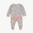 A baby long-sleeve footed sleeper with a pink floral print, featuring a solid pink ruffle trim across the middle and pink cuffs and toe.
