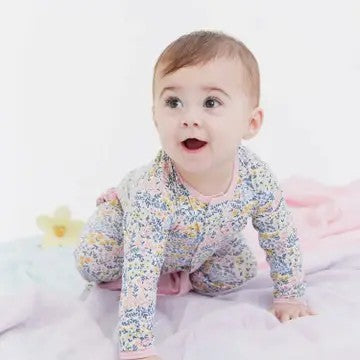 Baby wearing a floral onesie on a light pink background